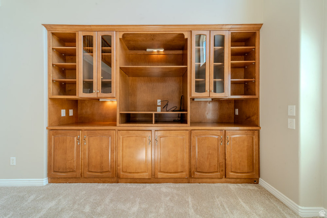 598 Hollow Creek Road Draper, UT 84020 - Photo 28 of 110 Integrated wood-finish entertainment center with extensive shelving, glass-front cabinetry, under-cabinet lighting, and lower storage cabinets