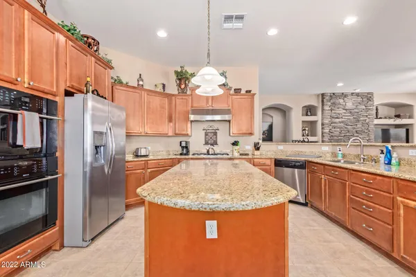 a kitchen with stainless steel appliances granite countertop a sink a stove and a refrigerator