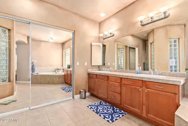 a spacious bathroom with a sink a mirror a bathtub and next to a window