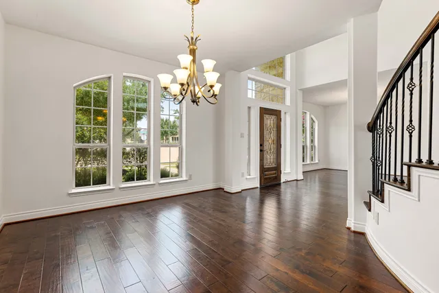 a view of a room with wooden floor chandelier and windows
