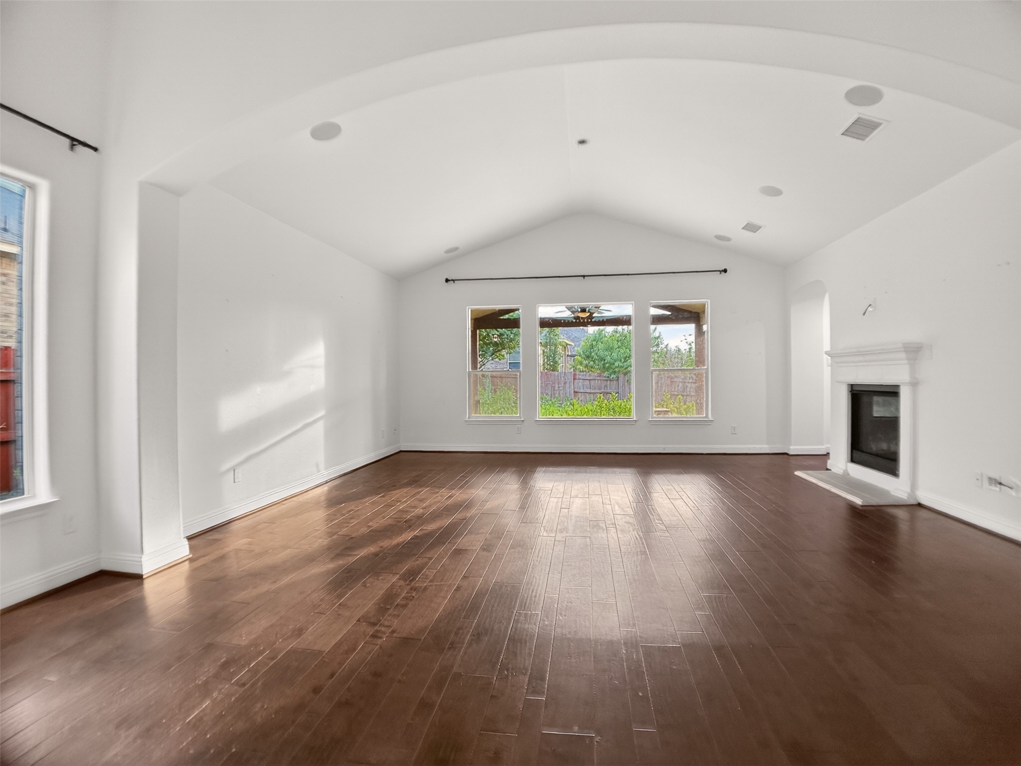 1505 Long Shadow Lane Georgetown, TX 78628 - Photo 9 of 28 Spacious room featuring vaulted ceilings, rich wood-finish flooring, a white mantel fireplace with hearth, and multiple windows offering ample natural light