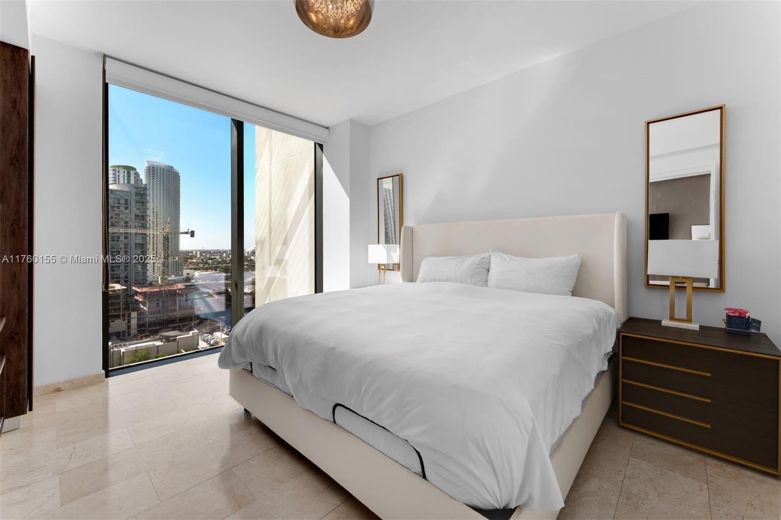 68 Southeast 6th Street, Unit 1404 Miami, FL 33131 - Photo 11 of 26 a bedroom with a bed and a large mirror next to a window