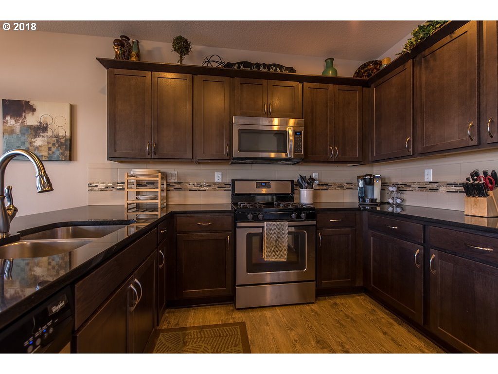 5047 Southwest 206th Place Beaverton, OR 97078 - Photo 8 of 28 a kitchen with granite countertop a sink dishwasher stove and microwave with wooden cabinets