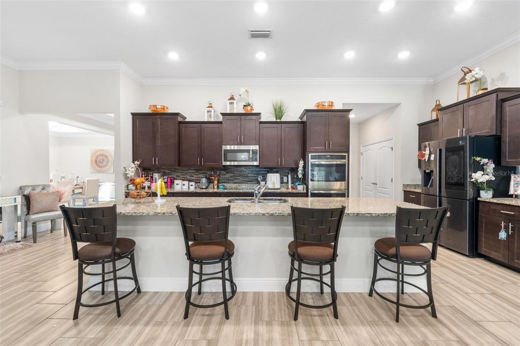 5615 Southwest 215th Terrace Newberry, FL 32669 - Photo 11 of 45 a dining hall with stainless steel appliances kitchen island granite countertop a dining table chairs and granite counter tops
