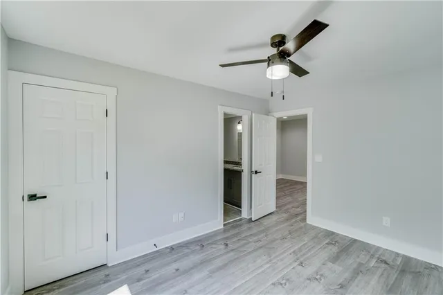 an empty room with wooden floor ceiling fan and windows