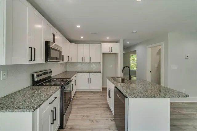 a kitchen with granite countertop a sink stove and refrigerator