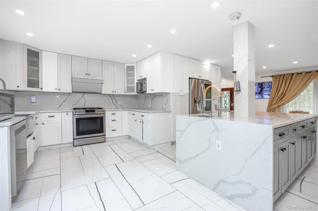 a kitchen with stainless steel appliances granite countertop a stove a sink and white cabinets