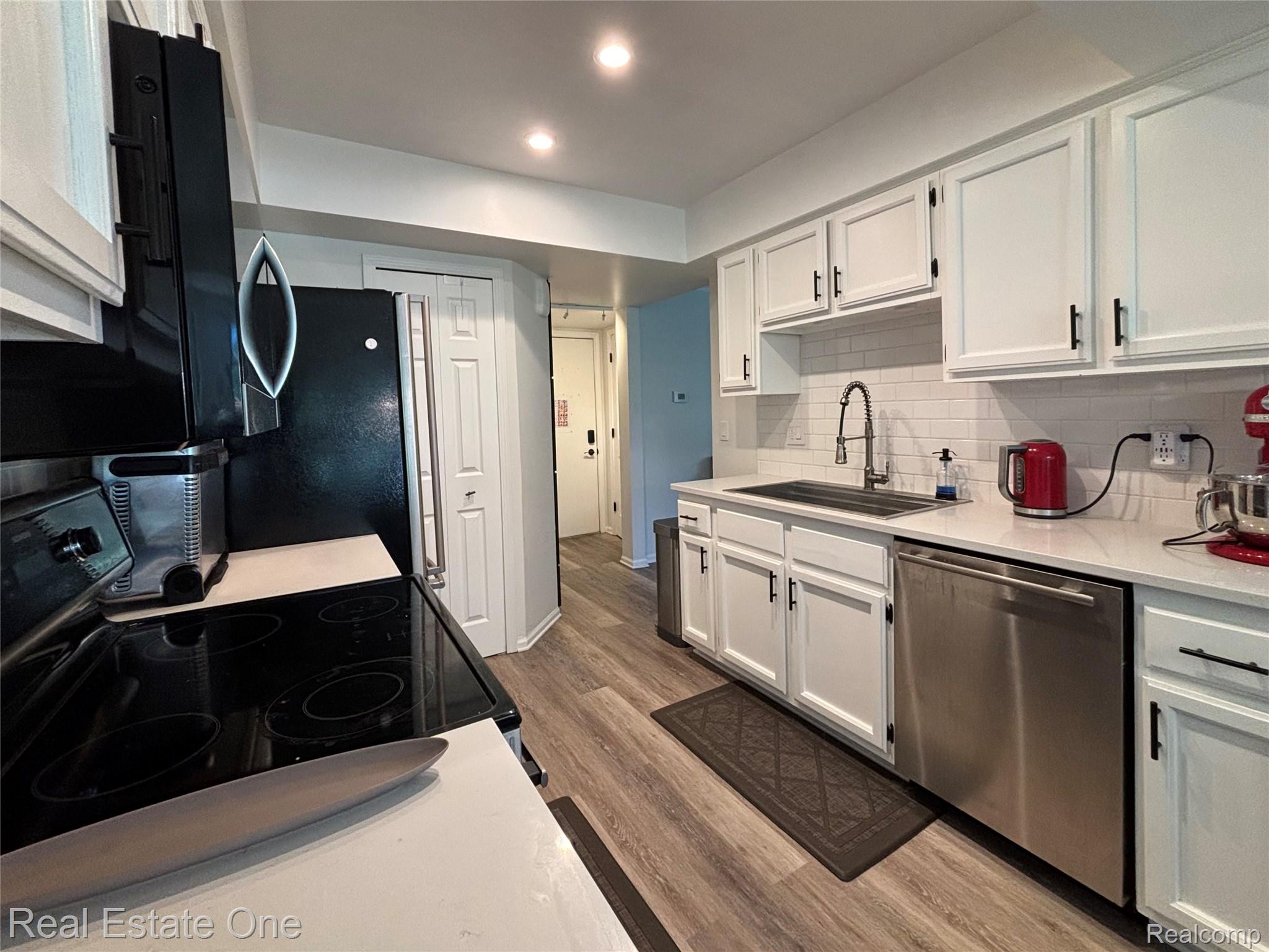 66 Meadow Wood Drive Rochester, MI 48307 - Photo 10 of 20 Modern kitchen featuring white shaker cabinetry, stainless steel appliances, a subway tile backsplash, light-toned countertops, and wood-finish flooring