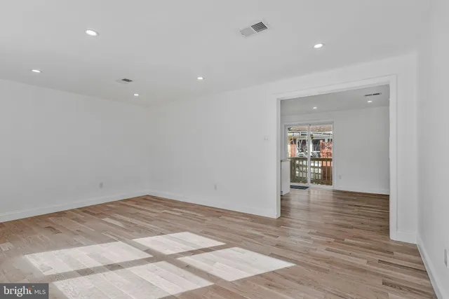 a view of an empty room with wooden floor and a bathroom