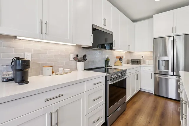 a kitchen with cabinets stainless steel appliances and wooden floor