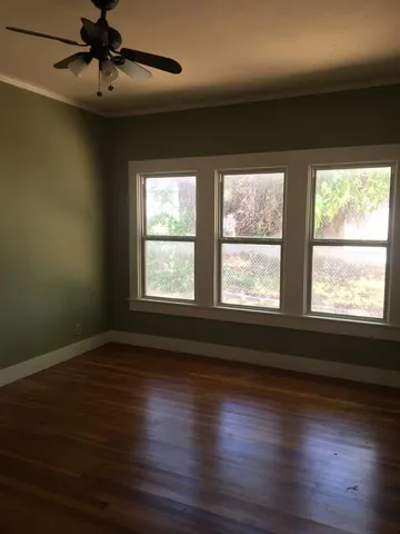 an empty room with wooden floor fireplace and windows