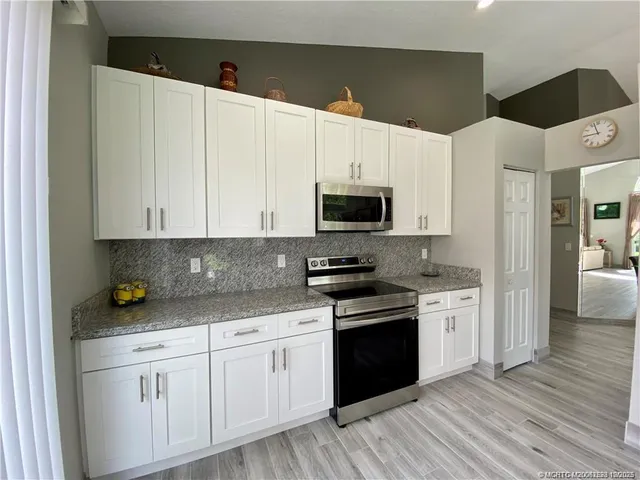 a kitchen with stainless steel appliances white cabinets and wooden floors