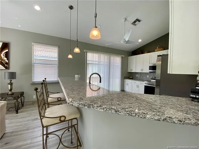 a kitchen with stainless steel appliances granite countertop a stove a sink dishwasher and white cabinets with wooden floor