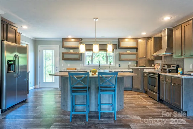 a kitchen with stainless steel appliances granite countertop a stove top oven a sink dishwasher a dining table and chairs with wooden floor