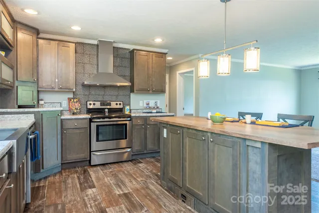 a kitchen with stainless steel appliances a sink a stove a refrigerator cabinets and a window