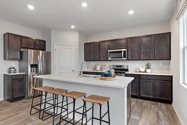 a kitchen with stainless steel appliances granite countertop a stove a sink a microwave a refrigerator and cabinets