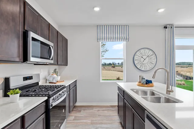 a kitchen with stainless steel appliances granite countertop a stove a sink and a microwave