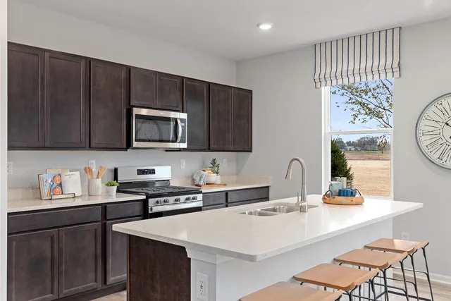 a kitchen with stainless steel appliances a sink a stove a microwave a refrigerator and cabinets