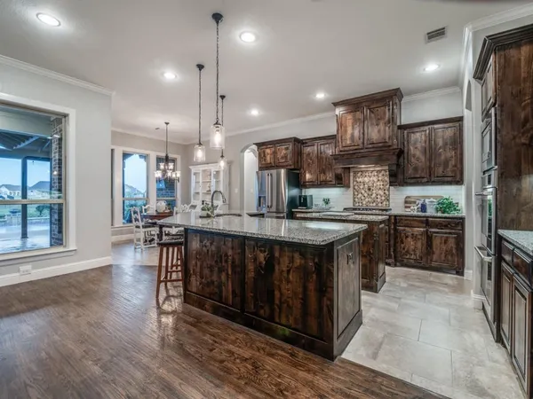 a kitchen with stainless steel appliances granite countertop a stove a sink a refrigerator and a wooden cabinets