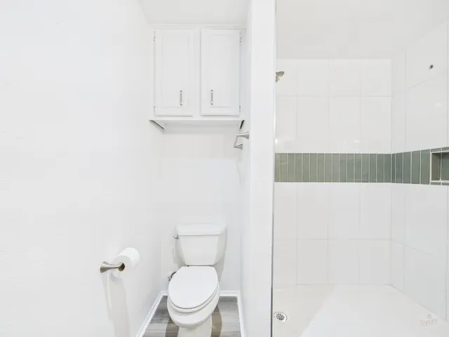 a white toilet sitting next to a shower