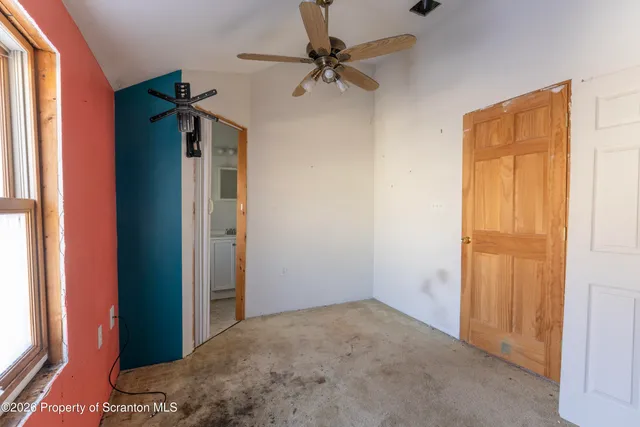 an empty room with windows and a ceiling fan
