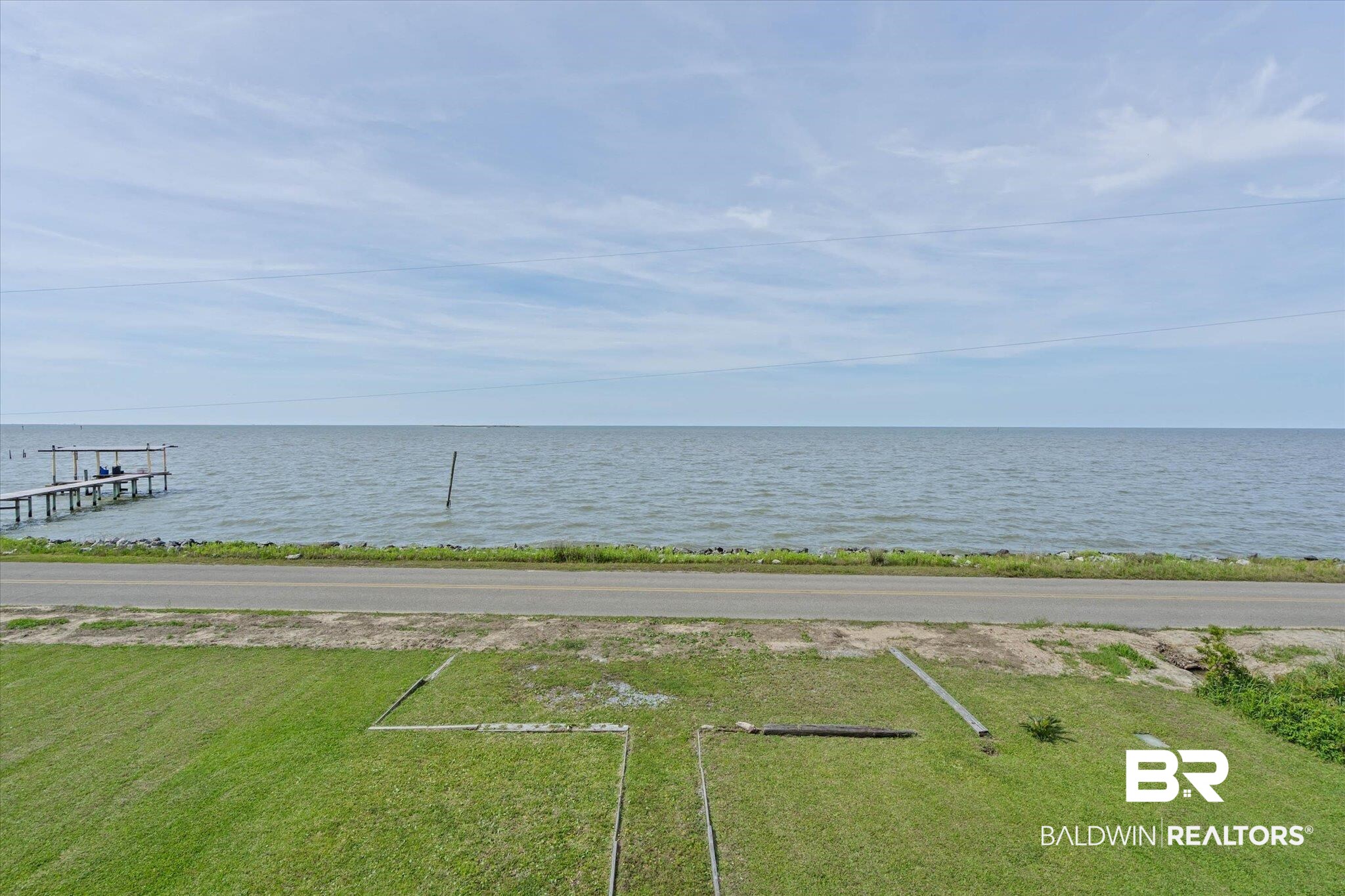 9100 Shell Belt Road Coden, AL 36523 - Photo 5 of 38 Waterfront parcel featuring a paved road frontage, lush green lawn, and direct water access with a private pier