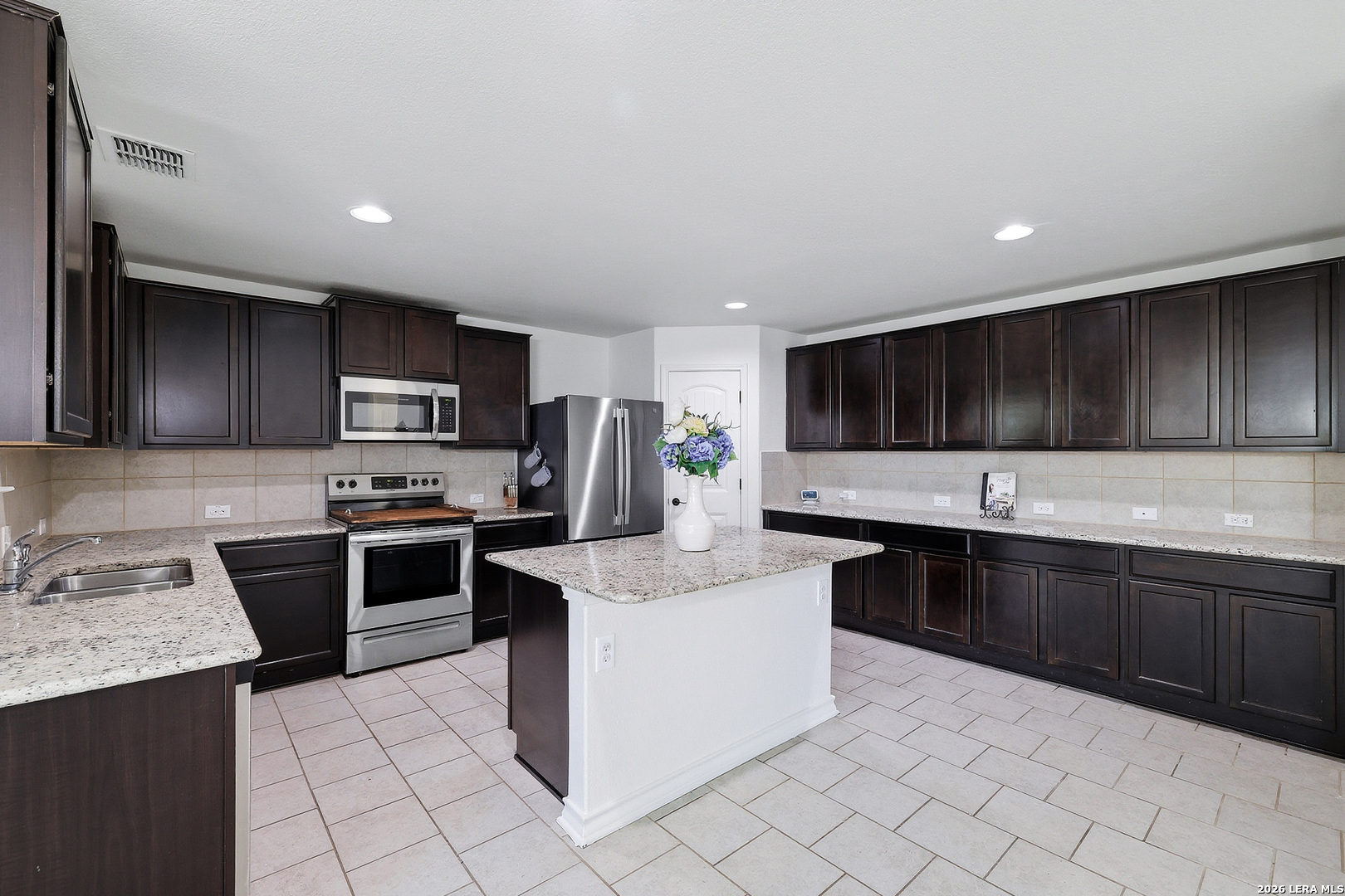 7435 Rigel Chase San Antonio, TX 78252 - Photo 18 of 38 a kitchen with stainless steel appliances granite countertop a sink counter space cabinets and a large window