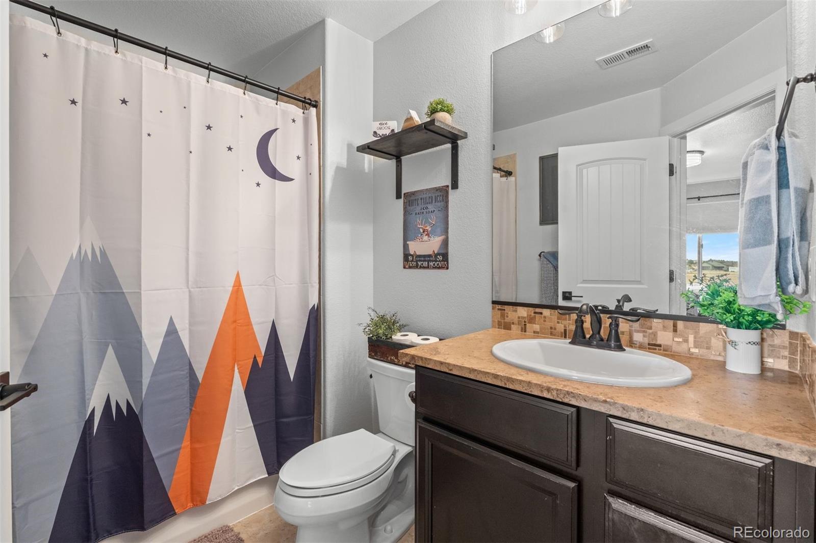32335 Legacy Ridge Street Elizabeth, CO 80107 - Photo 21 of 50 a bathroom with a sink a toilet a mirror a vanity and shower