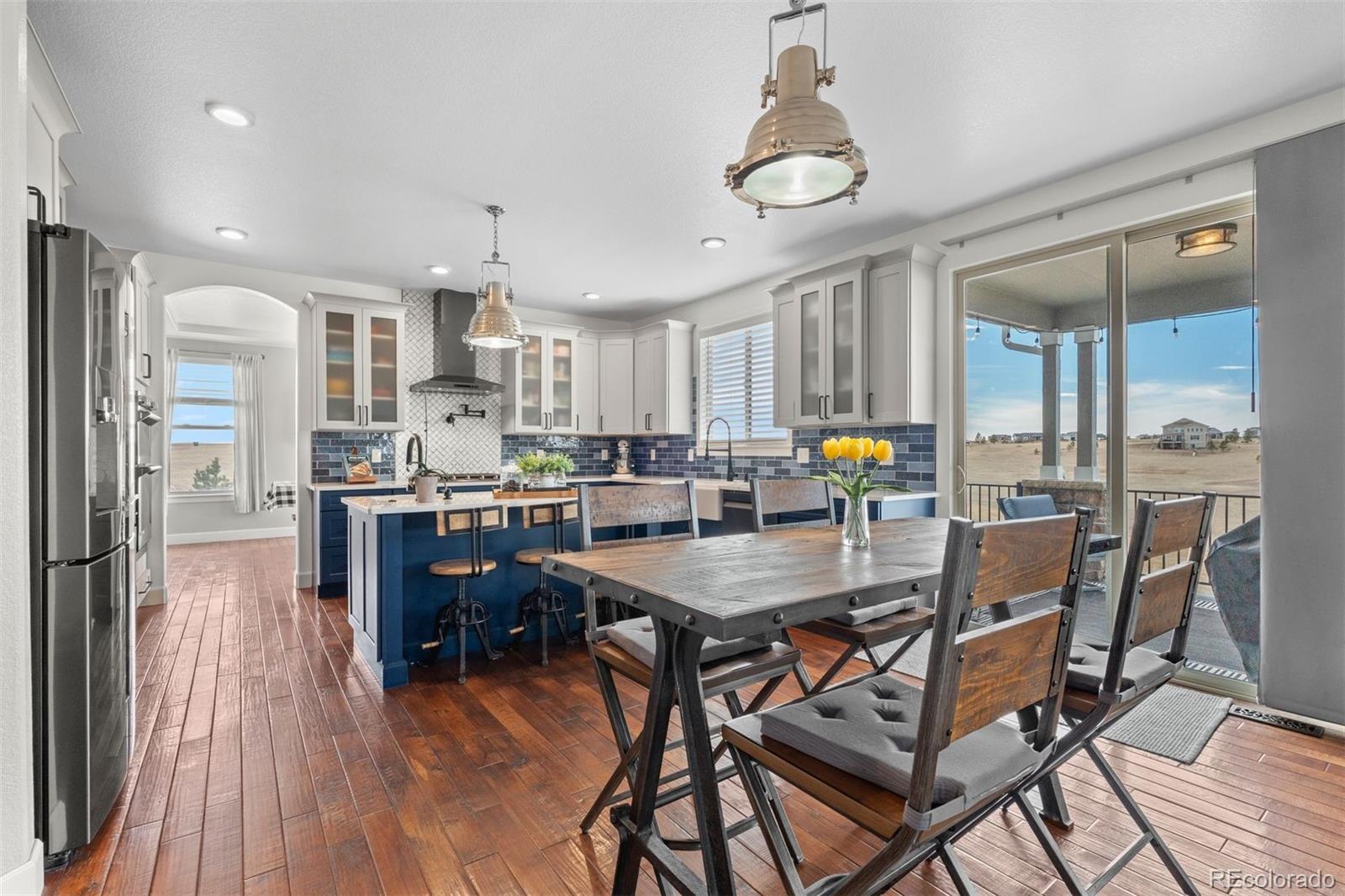 32335 Legacy Ridge Street Elizabeth, CO 80107 - Photo 6 of 50 a kitchen with stainless steel appliances a dining table chairs and wooden floor