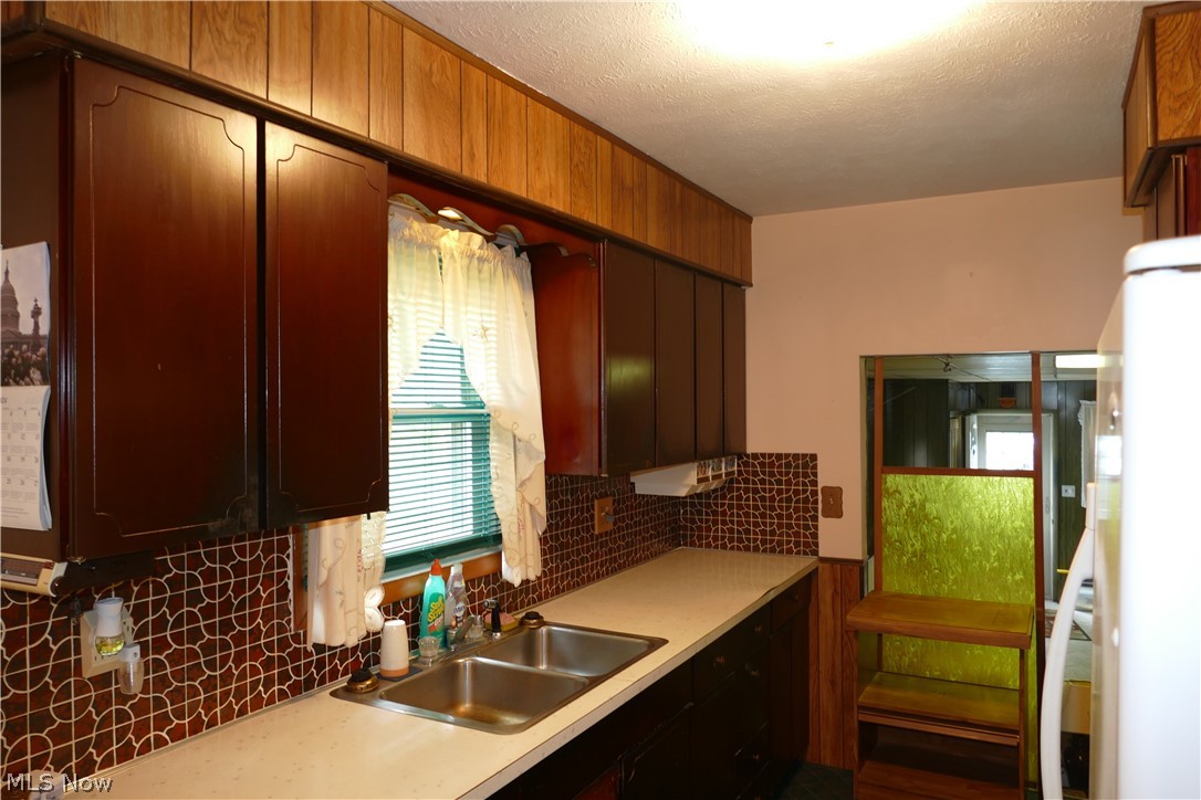 8661 Ravenna Road Chardon, OH 44024 - Photo 13 of 16 Kitchen with a textured ceiling, tasteful backsplash, and sink