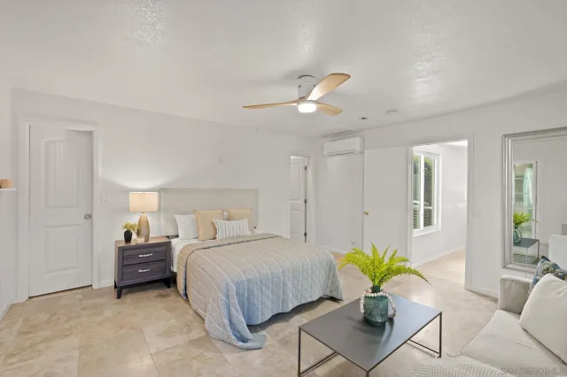 a bedroom with a bed a couch and potted plant