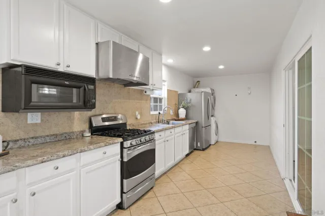 a kitchen with stainless steel appliances granite countertop a stove a sink and a microwave