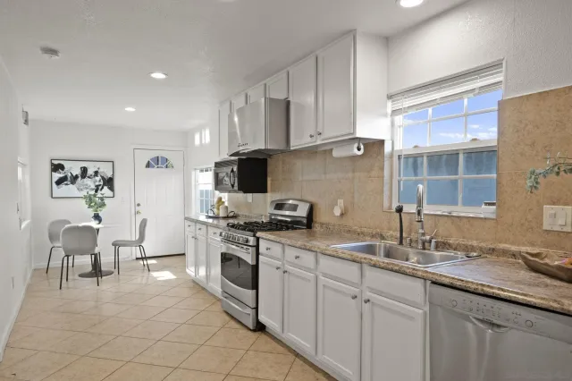 a kitchen with granite countertop a sink stainless steel appliances and cabinets