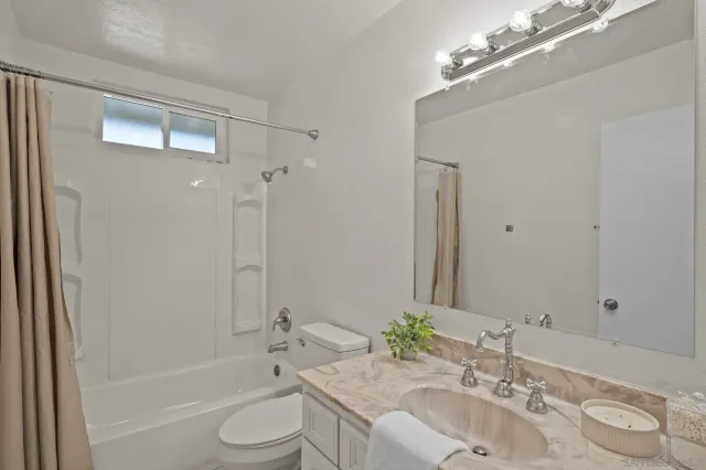 a bathroom with a granite countertop sink toilet a large mirror a bathtub and shower