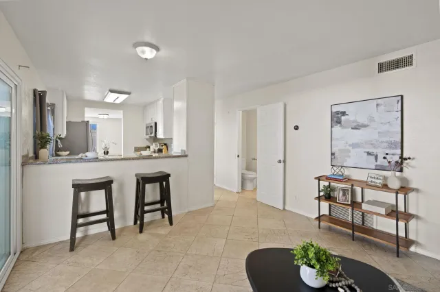 a living room with furniture and a dining table with kitchen appliances