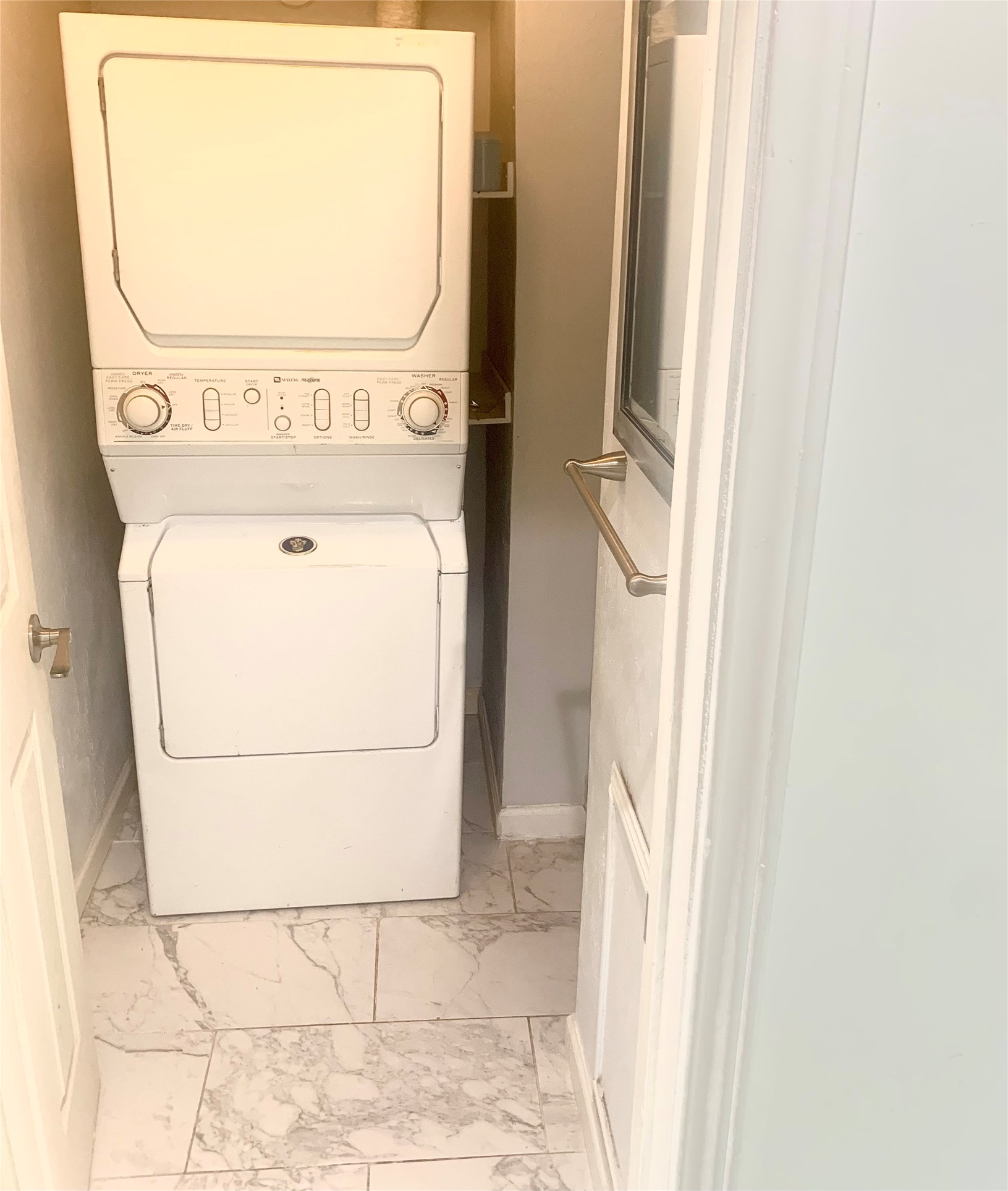 909 Silber Road, Unit 57J Houston, TX 77024 - Photo 13 of 14 Cozy laundry room with a stacked washer and dryer, featuring sleek marble-patterned tile flooring.