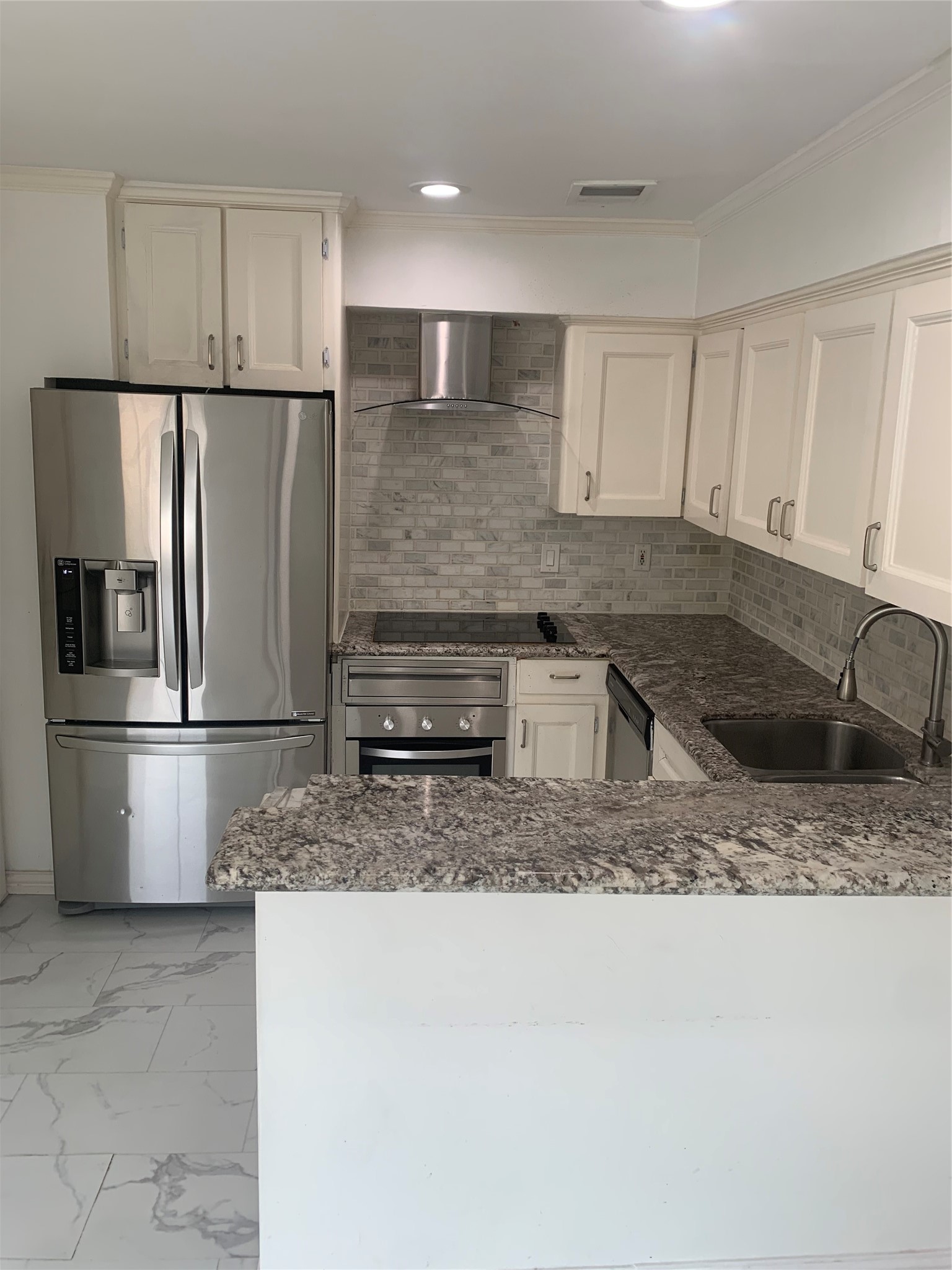 909 Silber Road, Unit 57J Houston, TX 77024 - Photo 3 of 14 Modern kitchen with stainless steel appliances, granite countertops, and white cabinetry. Features a sleek backsplash and recessed lighting, offering a clean and bright atmosphere.