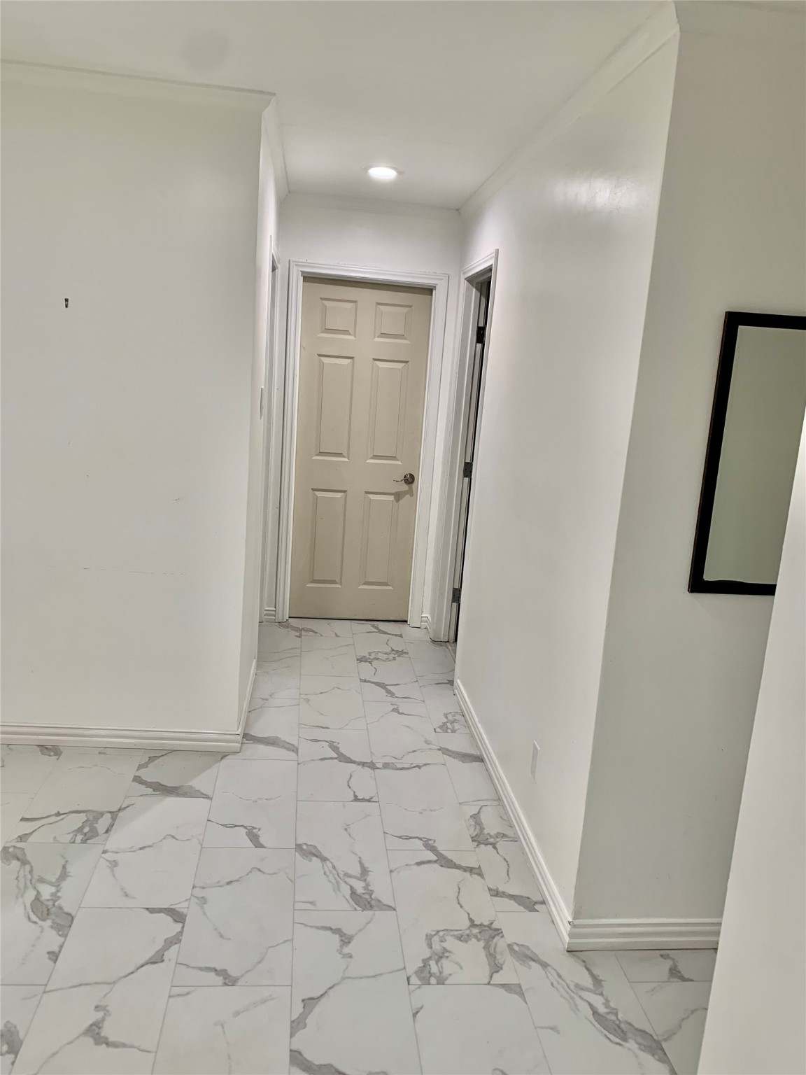 909 Silber Road, Unit 57J Houston, TX 77024 - Photo 5 of 14 This photo shows a bright, clean hallway with white walls and modern patterned flooring. There are doors leading to other rooms, creating a spacious and inviting entryway.