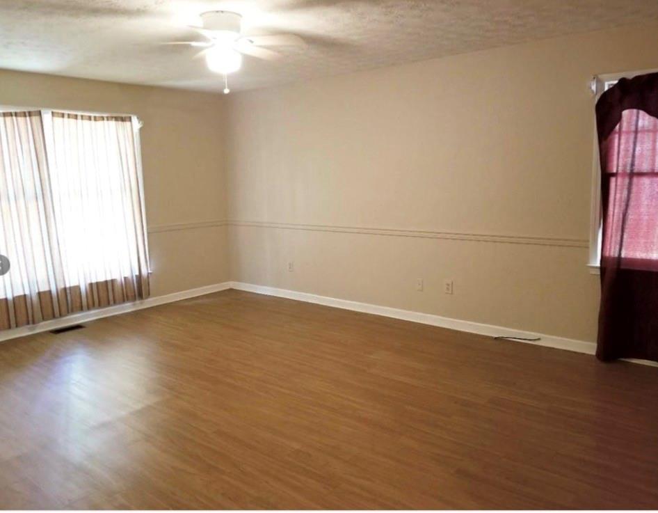 771 Lord Road Commerce, GA 30530 - Photo 5 of 16 an empty room with wooden floor and windows with curtains