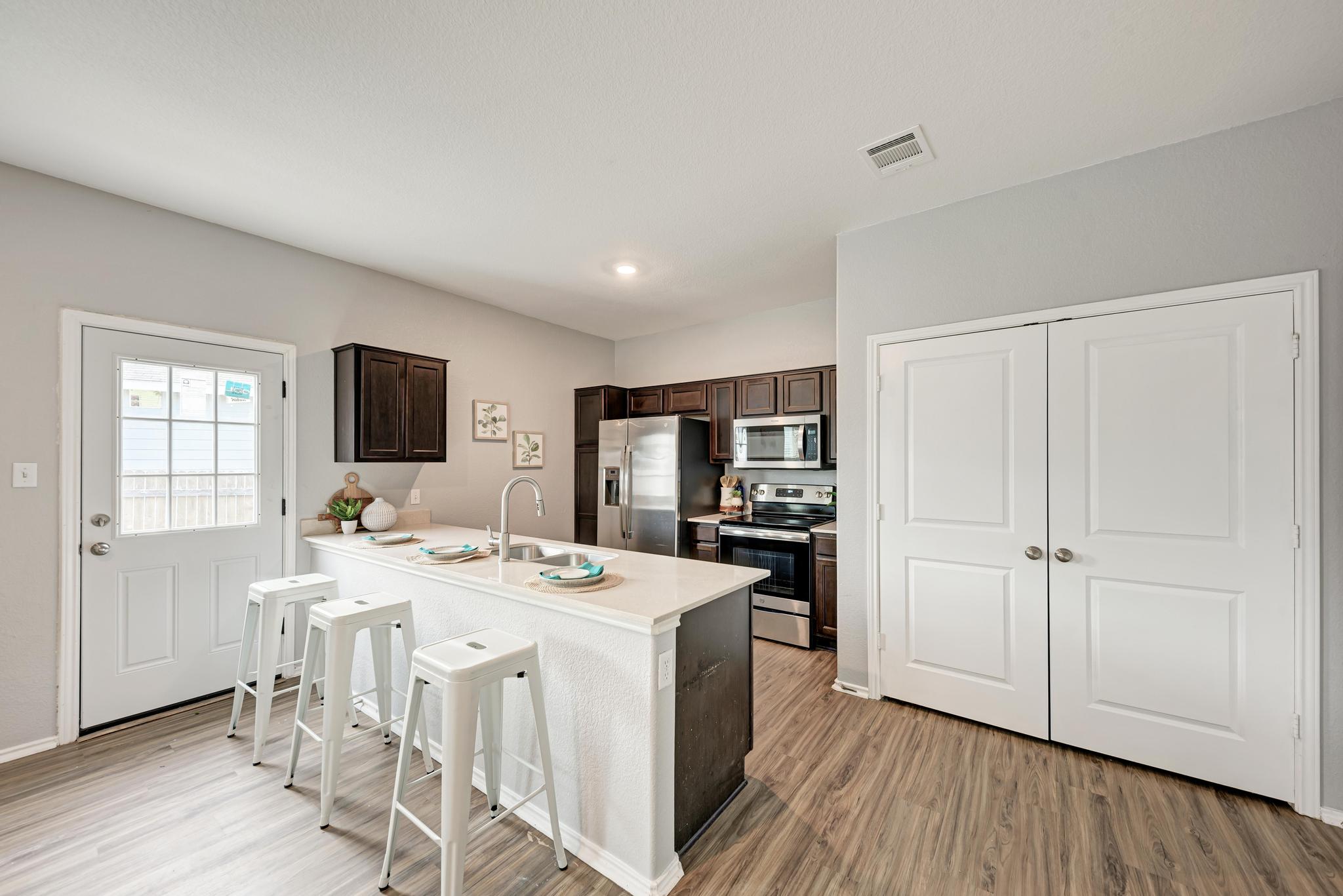 129 Vulcan Drive Jarrell, TX 76537 - Photo 13 of 35 a open kitchen with stainless steel appliances kitchen island granite countertop a stove a sink a refrigerator and white cabinets with wooden floor
