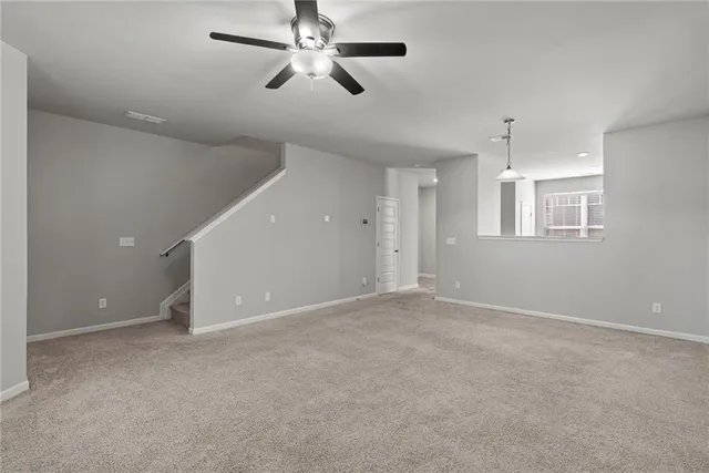 an empty room with chandelier fan and windows