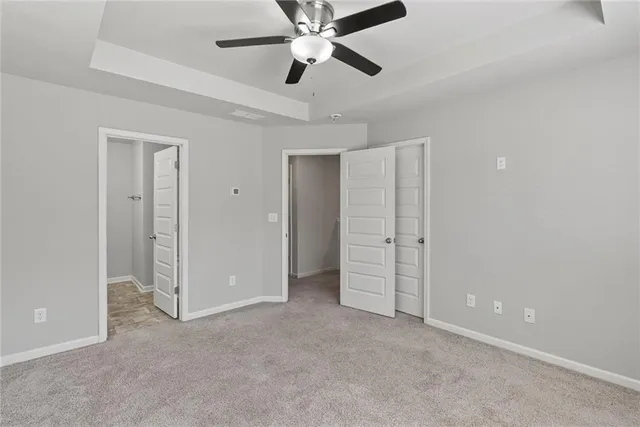an empty room with closet and a ceiling fan
