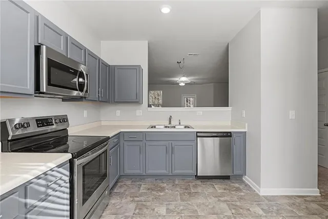 a kitchen with stainless steel appliances granite countertop a stove top oven a sink dishwasher and a microwave oven with wooden cabinets