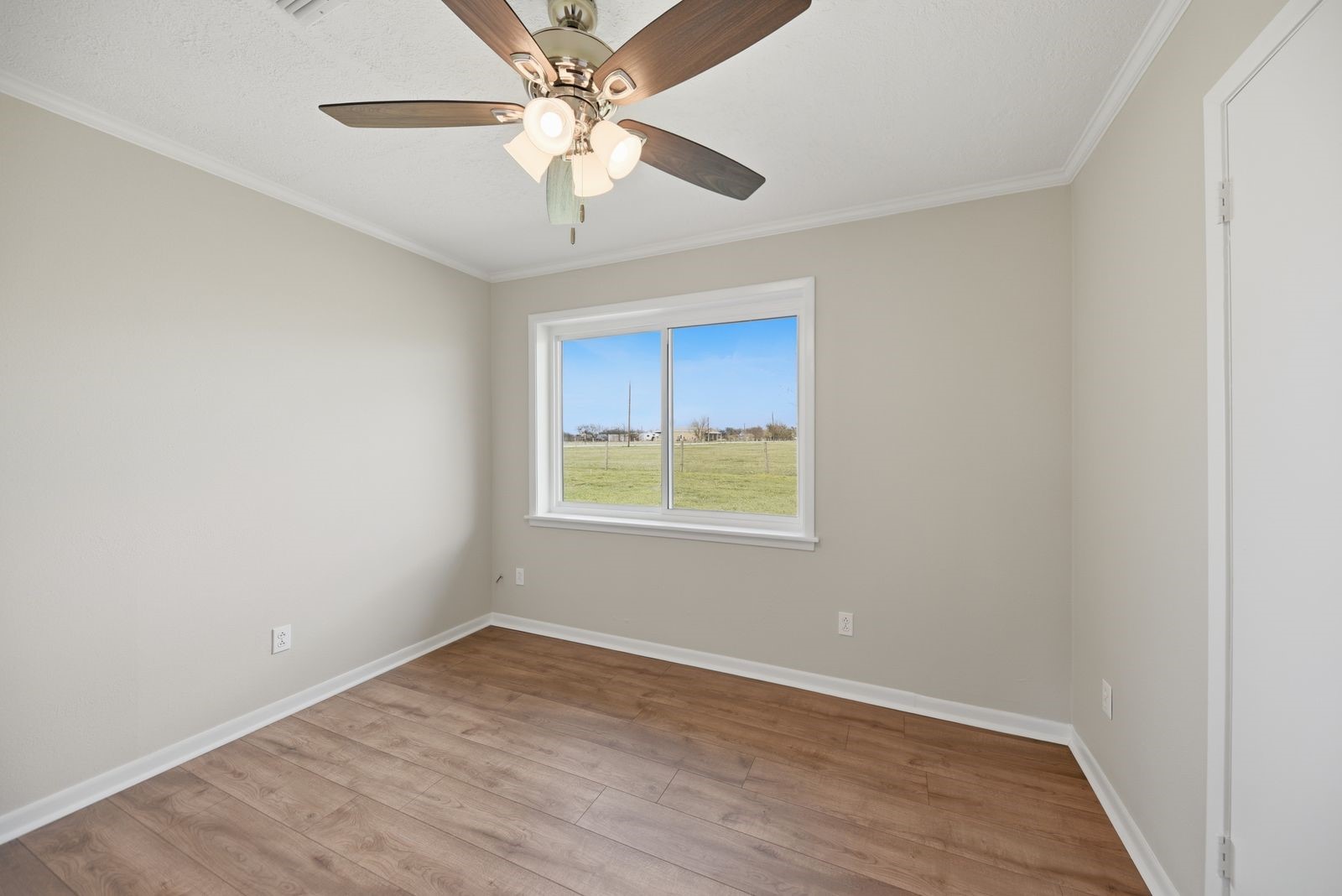 3249 Newsom Road Bellville, TX 77418 - Photo 10 of 20 an empty room with wooden floor chandelier fan and windows