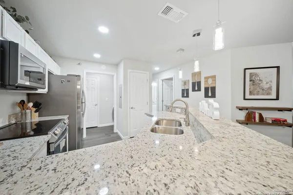 a kitchen with stainless steel appliances kitchen island granite countertop a sink refrigerator and microwave