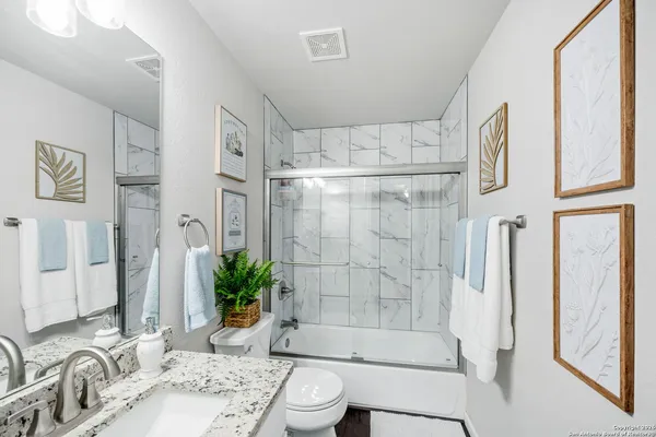 a bathroom with a granite countertop sink a toilet and shower