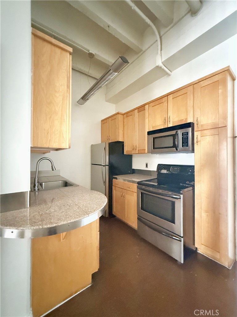 312 West 5th Street, Unit 903 Los Angeles, CA 90013 - Photo 11 of 12 a kitchen with stainless steel appliances granite countertop a sink a stove a refrigerator and a microwave