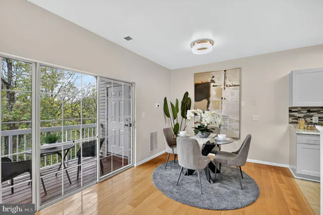 a dining room with furniture a floor to ceiling window and wooden floor