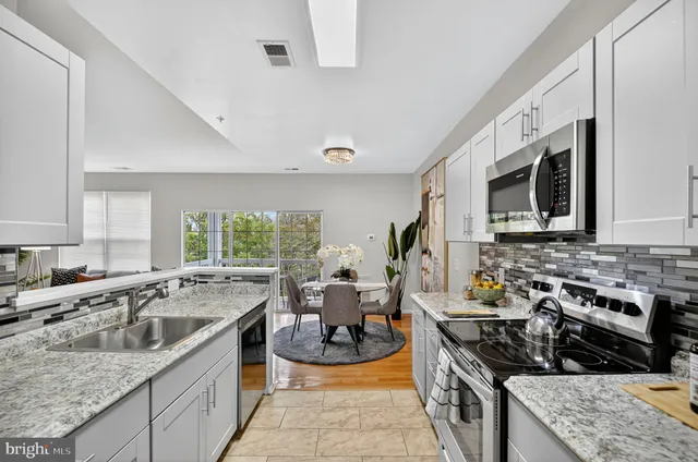 a kitchen with stainless steel appliances granite countertop a sink stove and microwave