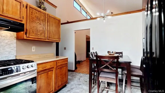 a kitchen with stainless steel appliances granite countertop a stove top oven a dining table and chairs with wooden floor